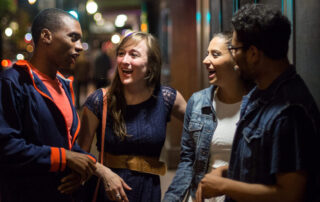 Students Talk On Outside On Green Street At Night.
